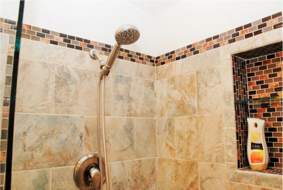 Close up of shower head and shampoo bottle niche