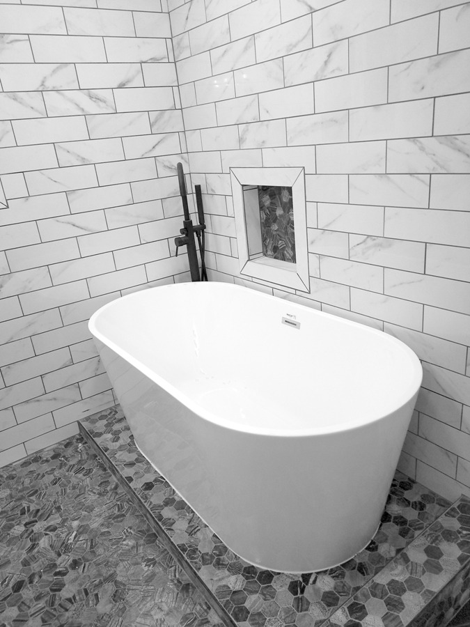 Modern stand-alone soaking tub with tile floor & tub surround